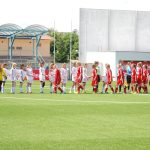 Jogadoras de futebol cumprimentam-se no campo antes de uma partida.