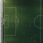 Vista aérea de um campo de futebol com jogadores em ação durante uma partida.
