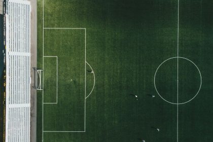 Vista aérea de um campo de futebol com jogadores em ação durante uma partida.
