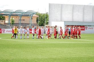 Jogadoras de futebol cumprimentam-se no campo antes de uma partida.