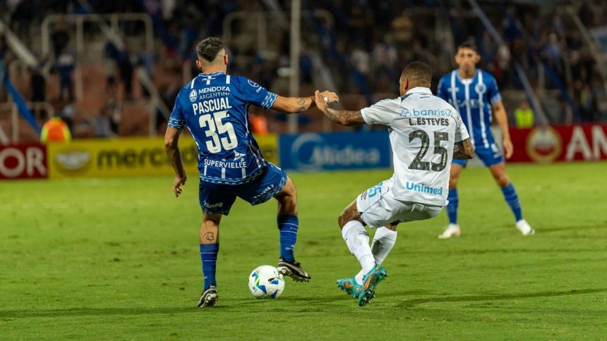 Jogadores disputam a bola durante uma partida de futebol em um gramado.