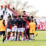 Jogadores de futebol comemoram juntos uma vitória em campo.