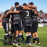 Jogadoras de futebol comemoram um gol durante uma partida em um estádio lotado