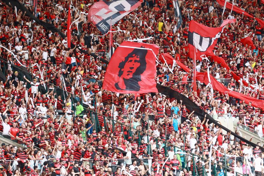 Torcedores do Flamengo, vestidos de vermelho e preto, comemoram nas arquibancadas do Maracanã.
