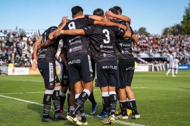 Jogadoras de futebol comemoram um gol durante uma partida em um estádio lotado